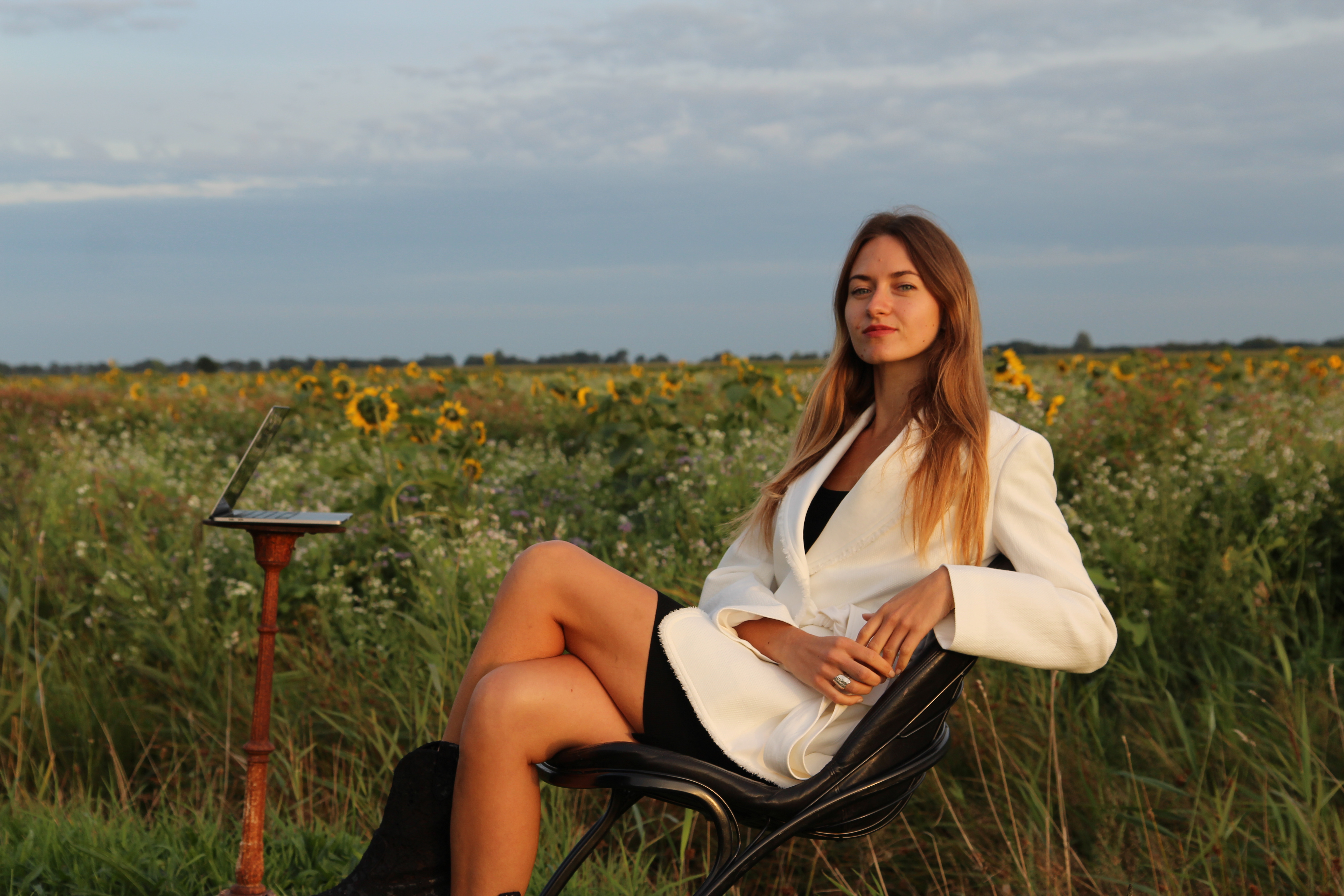 Ulyana Sarana seated in a field, with a laptop beside her
